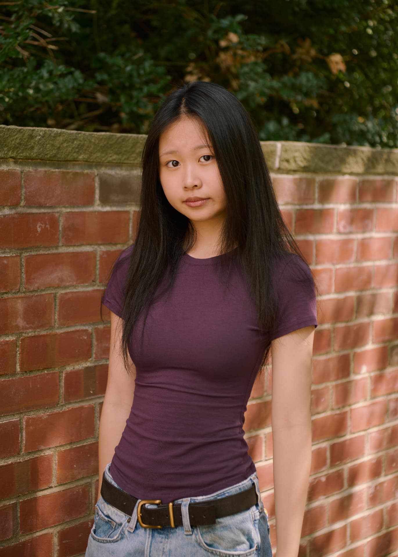 Portrait of Belle Ren, the creator of Sweet Rot, standing in front of a brick wall